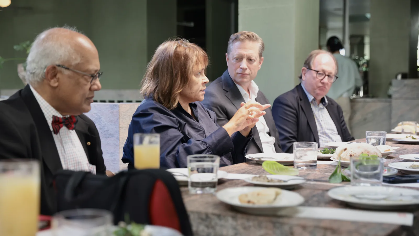 Four consultants at a Mindhive members' lunch, one of them making a point with her hands while the others listen.